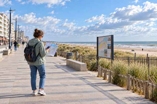 Voyageuse consultant une carte sur la promenade de Malo-les-Bains avant sa visite de Dunkerque.